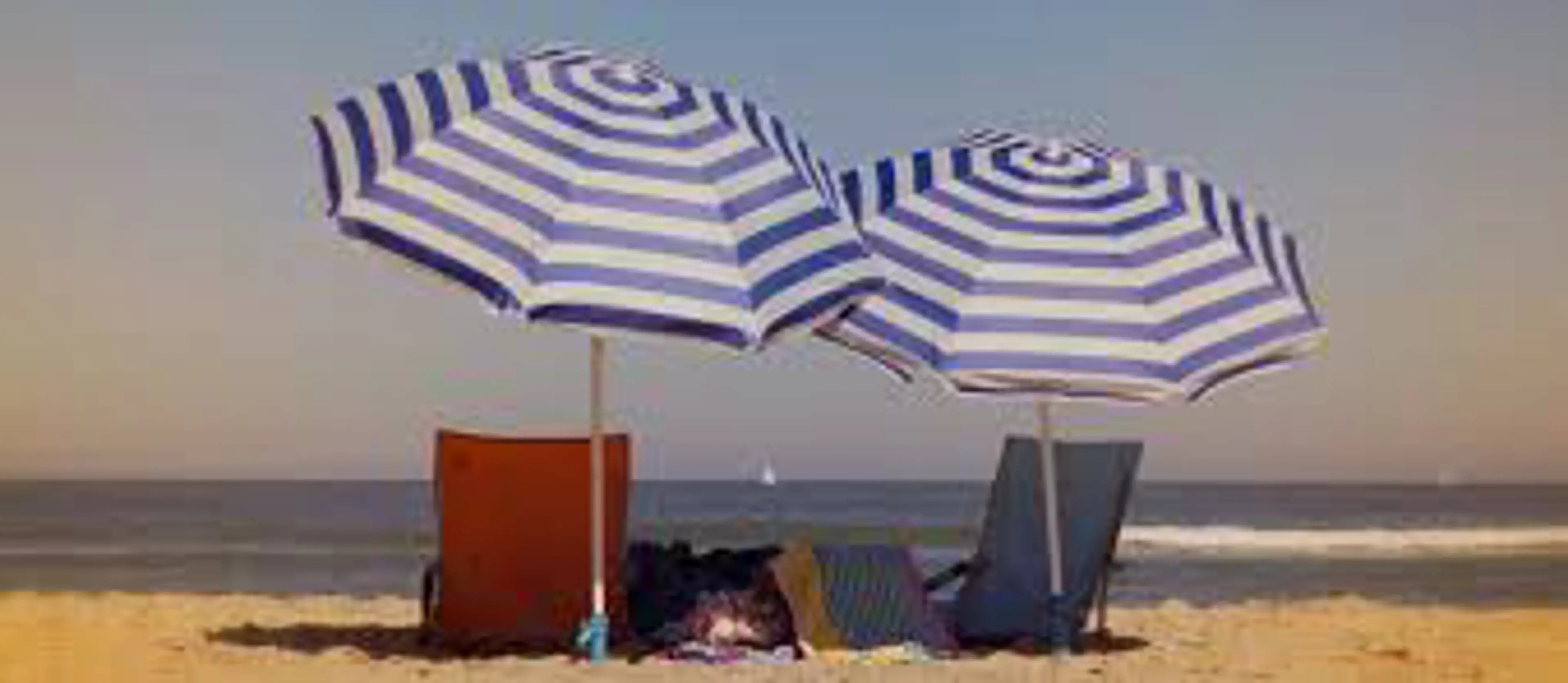 immagine di ombrellone e due sdraio in spiaggia